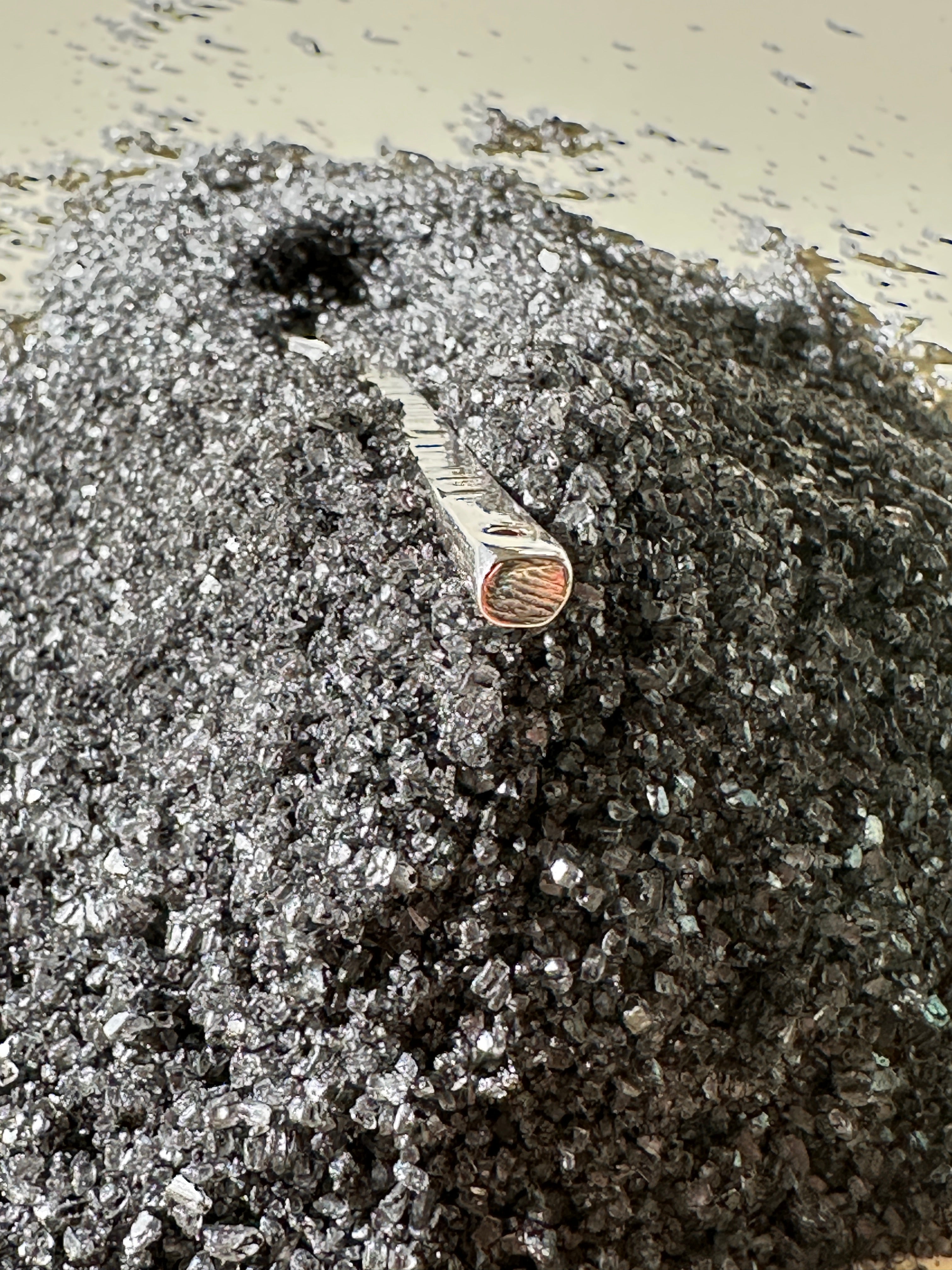 Small silver spoon handle on a textured surface with a beige background