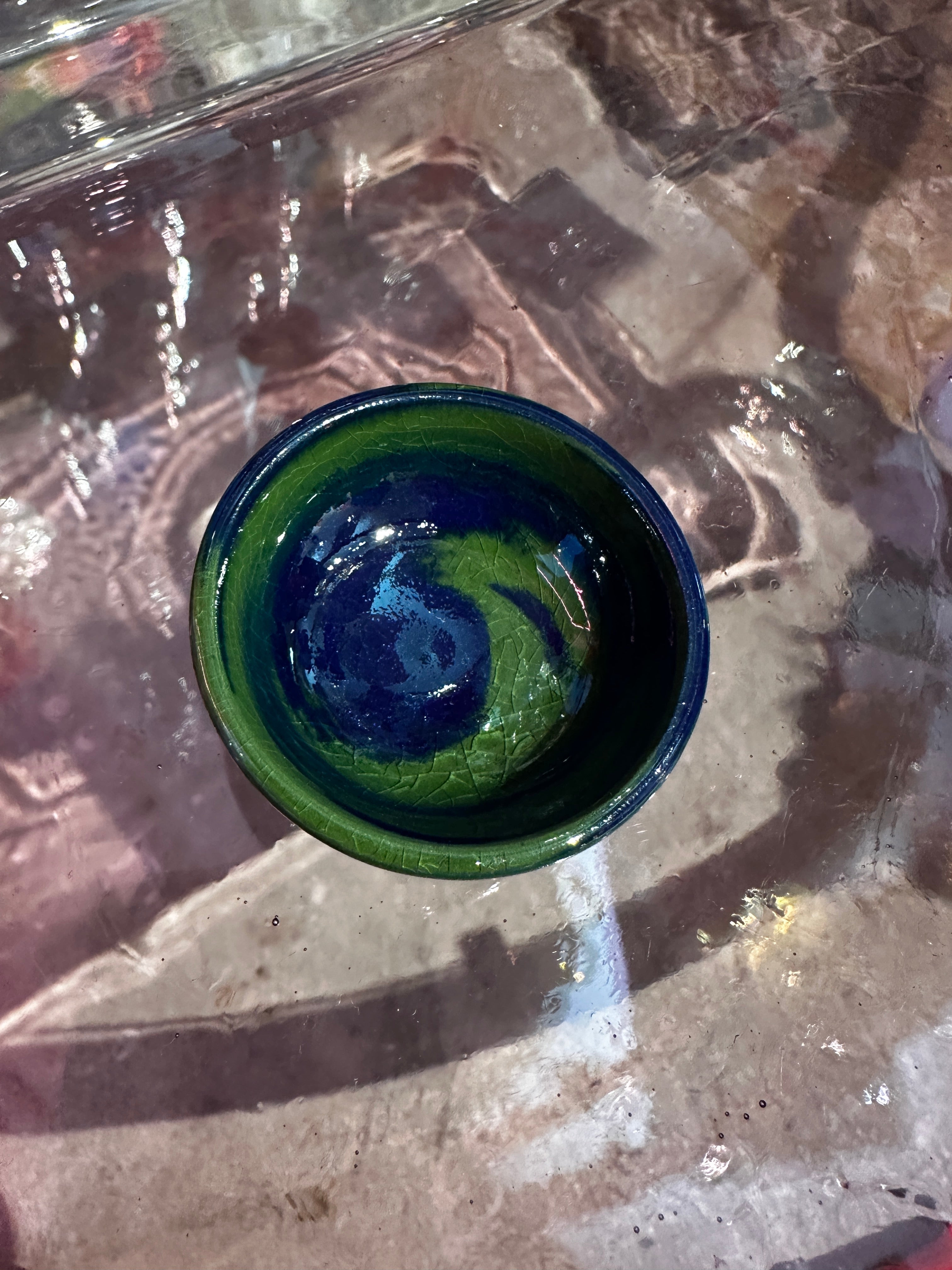 Green and blue ceramic bowl on a textured surface