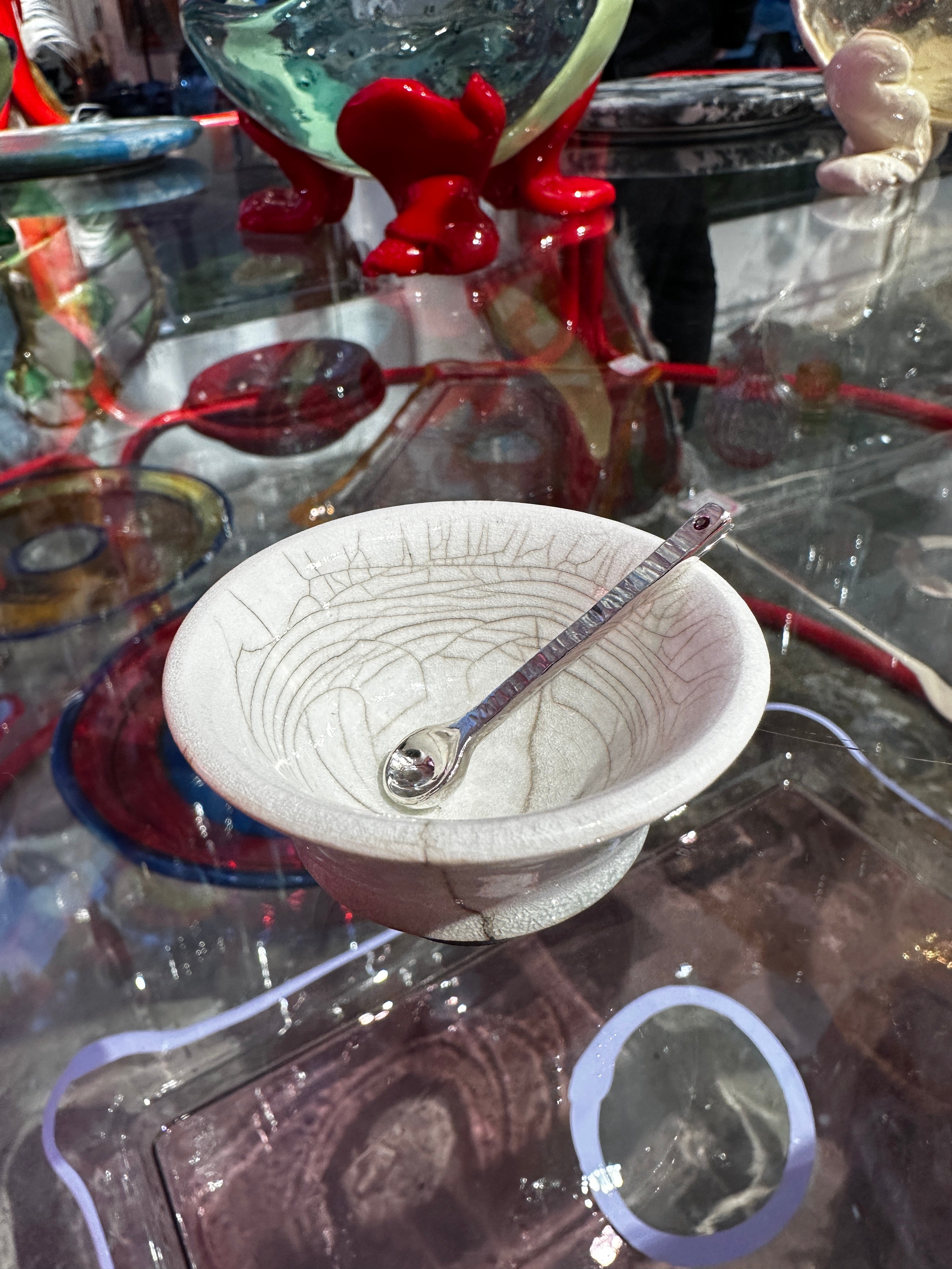 Silver salt spoon in white and black ceramic bowl on reflective surface