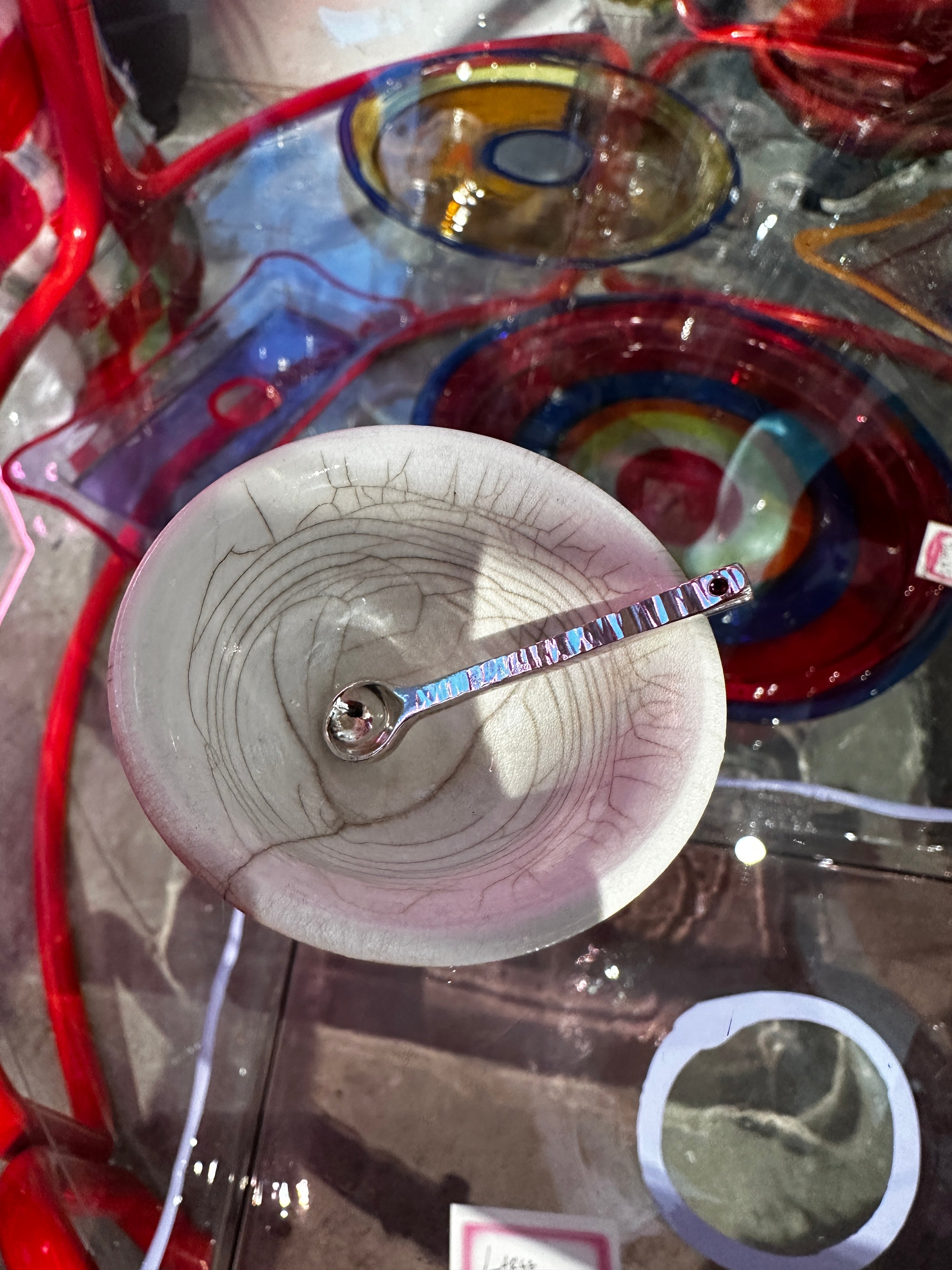 Silver salt spoon in white ceramic bowl on reflective surface
