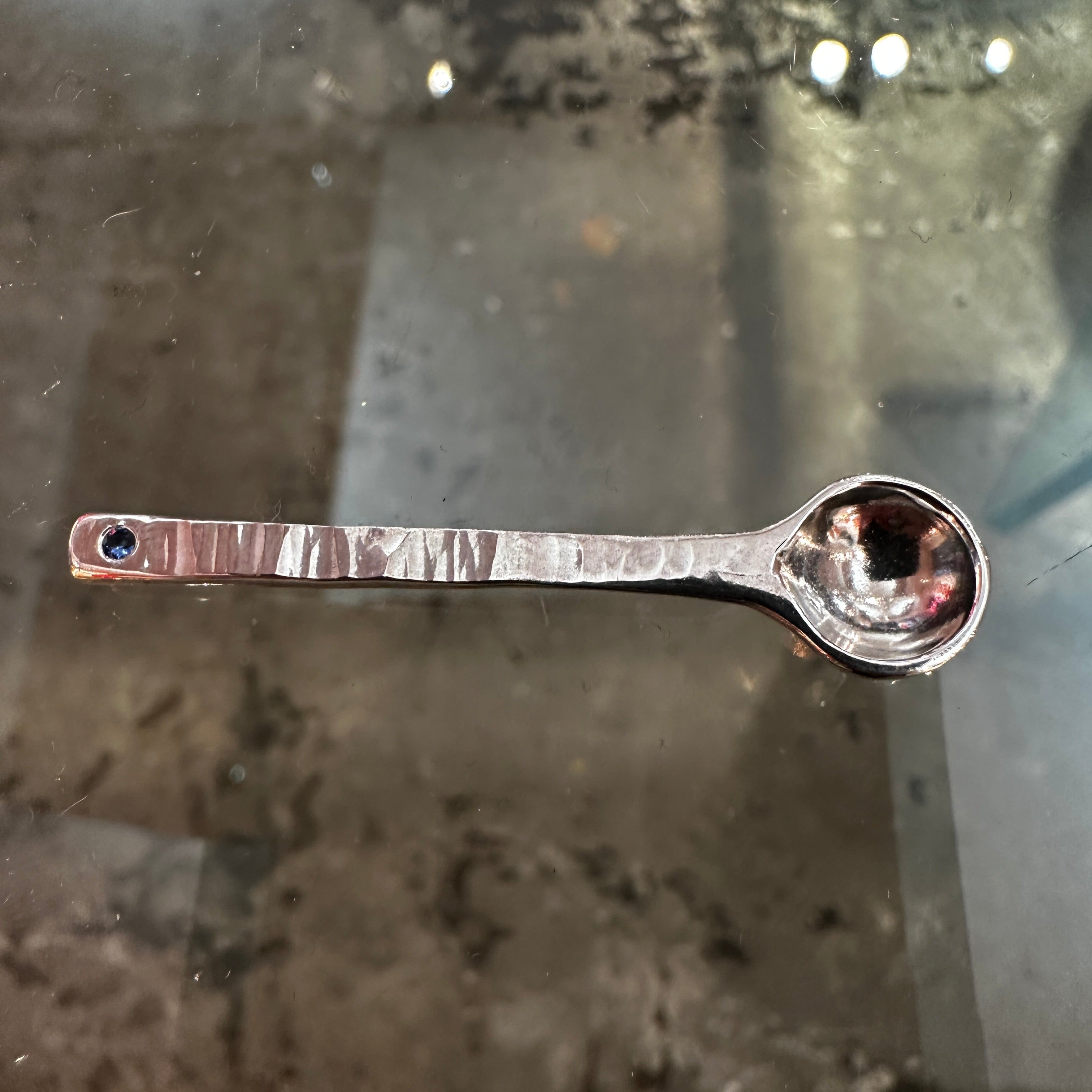 Silver salt spoon on a reflective surface
